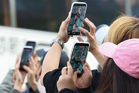 Onlookers use their phones to record footage
