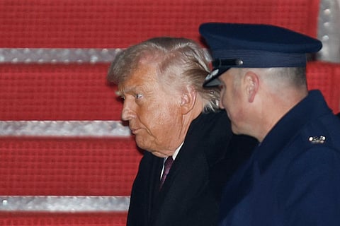 President Donald Trump, left, is greeted by Air Force Col. Christopher M. Robinson, commander of the 89th Airlift Wing, right, after walking down the stairs of Air Force One, upon his arrival at Joint Base Andrews, Md., Thursday, Jan. 22, 2026, after returning from the World Economic Forum in Davos, Switzerland.