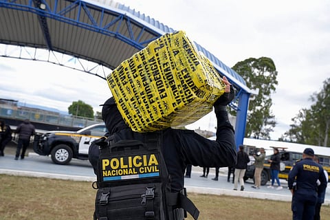 This handout picture released by Guatemala's National Civil Police press office shows members of the National Civil Police carrying packages of the seized 4.9 tonnes of cocaine during an operation at the port of Quetzal, in Escuintla, Guatemala City, on January 28, 2026.