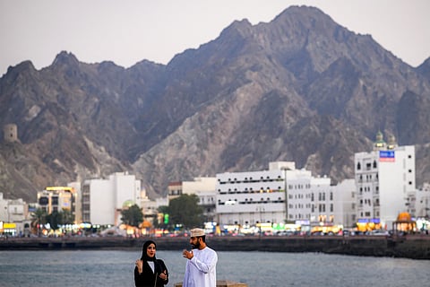 A man and a woman speak as they stand along the corniche at Sultan Qaboos port in Oman's capital Muscat on February 5, 2026.