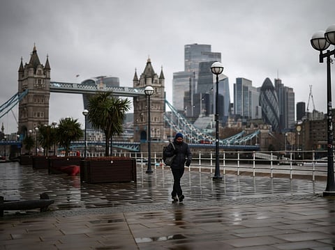 A pedestrian walks past Tower Bridge along the Thames in central London.