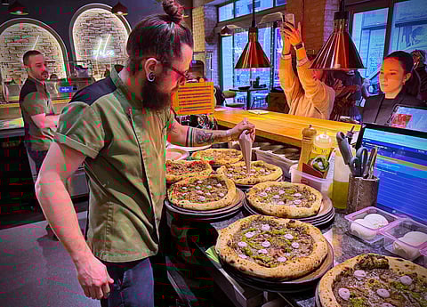 Laszlo Bardossy, head chef of the Neverland Pizzeria adds topping on the restaurant's Roman-era pizza in Budapest, Hungary, on Feb. 11, 2026. (AP Photo/Bela Szandelszky)