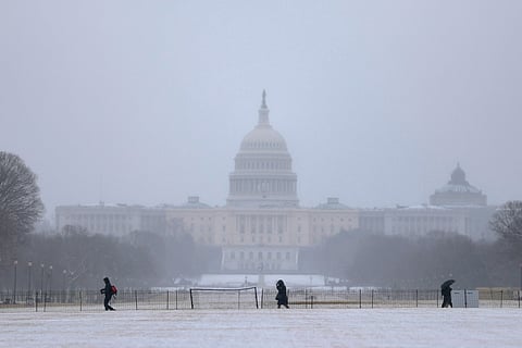 Individuals walk on the National Mall as snow falls on February 23, 2026 in Washington, DC. A major winter storm has hit the Northeast and Mid-Atlantic regions bringing heavy snowfall, and a blizzard warning has been issued for large areas of the East Coast.