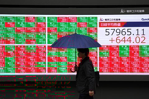 A pedestrian walks past an electronic quotation board displays numbers of the Nikkei Stock Average on the Tokyo Stock Exchange along a street in Tokyo. File photo taken on February 25, 2026.