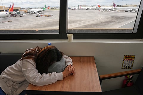 An overseas Filipino worker sleeps as she waits for updates on her cancelled flight to the Middle East at Manila's International Airport, Philippines