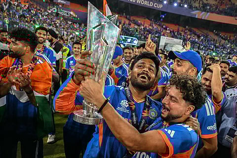 India's Sanju Samson (C) and Kuldeep Yadav (C, right) celebrate with the trophy during a victory lap after winning the 2026 ICC Men's T20 Cricket World Cup final match against New Zealand at the Narendra Modi Stadium in Ahmedabad on March 8, 2026.