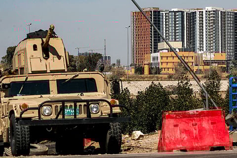 An Iraqi army armoured humvee vehicle is deployed near the banks of the Tigris River to protect the US Embassy headquarters (R) in Baghdad's fortified "Green Zone" on March 18, 2026.
