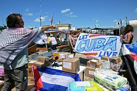 Brazilian activist Thiago Avila (L) gestures as he helps carry boxes with aid to be loaded on a boat that starts its journey to take humanitarian aid to Cuba, as part of the Convoy to Cuba, organised by left-wing activists from various countries in the Americas and Europe, in Puerto Progreso, Yucatan state, Mexico, on March 19, 2026.