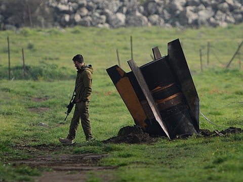 An Israeli soldier stands next to a fragment of a missile fired from Iran and intercepted by Israeli air defence system embedded in an open field in the Israeli-controlled Golan Heights.