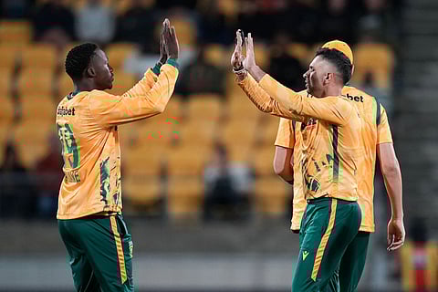 South Africa captain Keshav Maharaj (R) celebrates bowling New Zealand's Cole McConchie with teammate Andile Simelane during the fourth Twenty20 international cricket match between New Zealand and South Africa in Wellington on March 22, 2026.