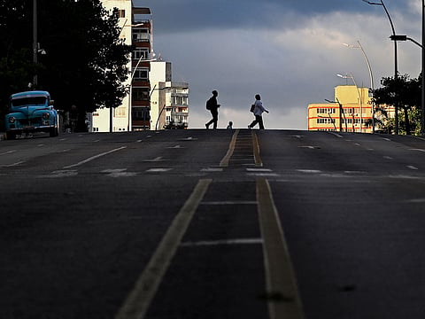 People cross a street during a nation wide blackout in Havana on March 22, 2026.