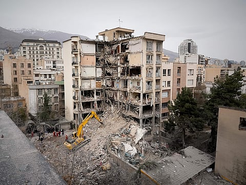 Iranian Red Crescent emergency workers use a bulldozer to clear rubble from a residential building that was hit in an earlier US-Israeli strike in Tehran, Iran, Monday, March 23, 2026.
