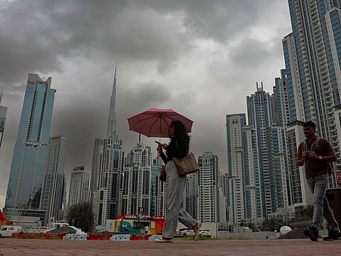 Dark clouds loom over Dubai’s iconic skyline, with the Burj Khalifa rising in the background.
