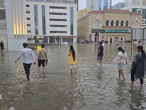 Residents navigate floodwaters in Sharjah streets on Friday.