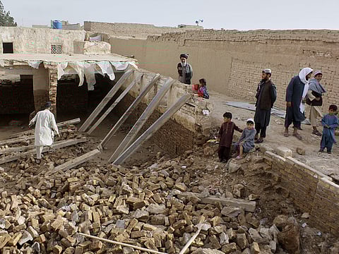 Locals inspect a damaged house following floods, landslides and thunderstorms in Kandahar province, Afghanistan, Sunday, March 29, 2026.