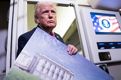 President Donald Trump holds a rendering of the proposed East Wing of the White House while speaking to members of the media onboard Air Force One on March 29, 2026 while en route to Joint Base Andrews, Maryland from West Palm Beach Florida.