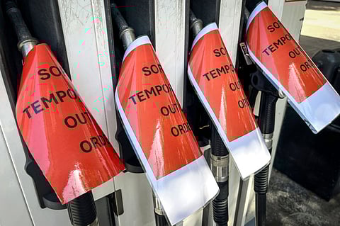 Signs cover petrol bowsers at a closed petrol station in Sydney on March 30, 2026. Australia will halve a tax on fuel to reduce costs for motorists experiencing soaring petrol prices due to war in the Middle East, Prime Minister Anthony Albanese said on March 30, 2026.