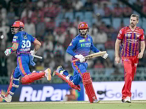 Delhi Capitals' Sameer Rizvi (C) and teammate Tristan Stubbs (L) run between the wickets as Lucknow Super Giants' Anrich Nortje looks on during their IPL match at the Ekana Cricket Stadium in Lucknow on April 1, 2026.