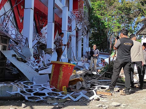 Police officers inspect a damaged building following an earthquake in Manado, North Sulawesi, Indonesia