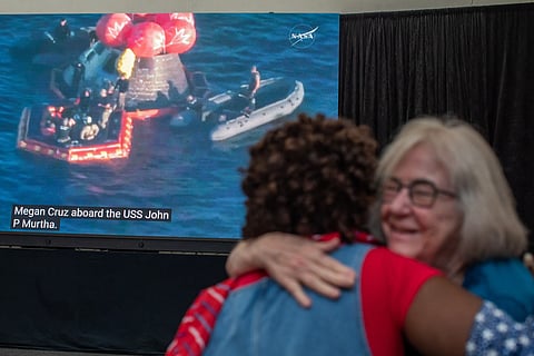 People hug as they watch a live broadcast of the return of the Artemis II crew members to Earth at the San Diego Air and Space Museum during a watch party for the crew's splash down in the Pacific Ocean, in San Diego, California, on April 10, 2026.