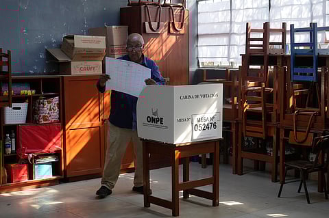 A voter looks at a ballot before marking his candidates during general elections in Lima, Peru, on Sunday, April 12, 2026. (AP Photo/Martin Mejia)