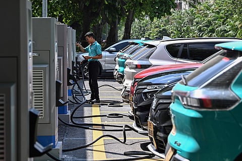 This picture taken on October 5, 2023 shows a driver charging a VinFast electric car at a charging station in Hanoi.