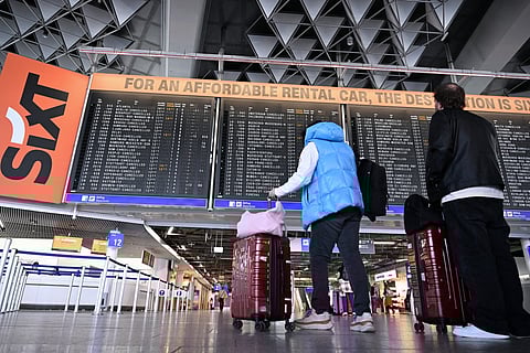 Passengers check a flight information display at Frankfurt Airport, Frankfurt am Main, western Germany, on April 15, 2026, as cabin crew union UFO urged members of Lufthansa cabin crew to stage a strike in a dispute over pay and pensions.