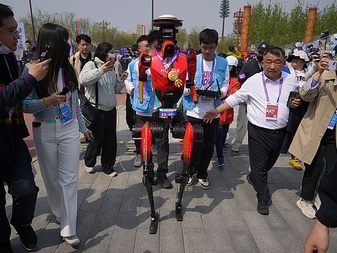 The winner of the humanoid robot half-marathon from Honor is chased by journalists after a press conference at the Beijing E-Town Half Marathon and Humanoid Robot Half-Marathon on the outskirts of Beijing.