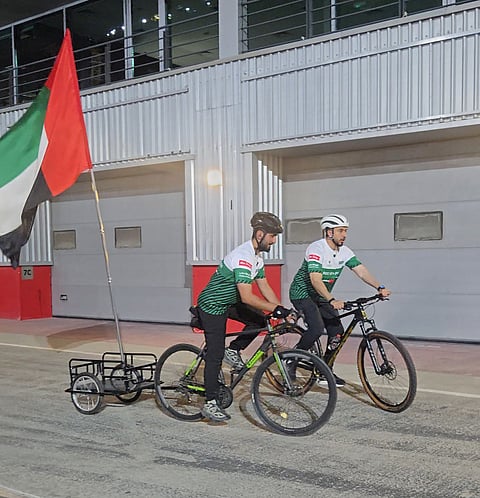 Dubai Police riders cycling with the UAE flag behind them