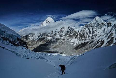 Mount Pumori, centre left, looms in the background as a mountaineer negotiates Khumbu Icefall to descend to Everest Base Camp, in Nepal, May 4, 2025.