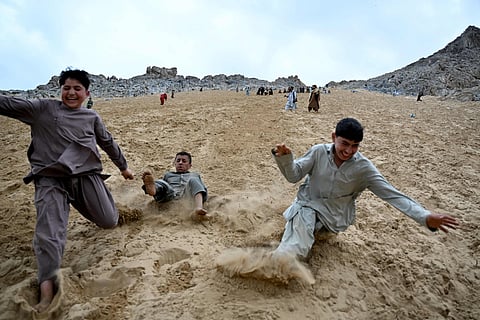 Afghan visitors enjoy rolling down a steep and sandy mountainside on a weekend at the Sayad area of Reg-e-Rawan in Kapisa province.