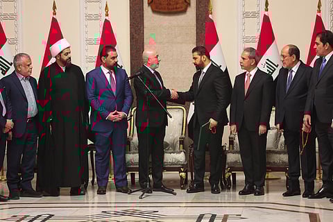 This handout photograph taken and released by the Iraqi Presidency Press Office on April 27, 2026 shows Iraq's President Nizar Amede (4th L) shaking hands with newly Iraq's Prime Minister designated Ali al-Zaidi (4th R), surrounded by Iraqi political leaders, at the Presidential Palace in Bagdad.