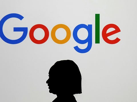 A woman walks by a giant screen displaying the Google logo at an event at the Paris Google Lab on the sidelines of the AI Action Summit in Paris