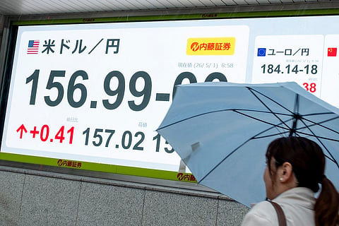 A woman walks past an electronic quotation boards displaying the foreign exchange rate of the Japanese yen against the US dollar along a street in Tokyo on May 1, 2026.
