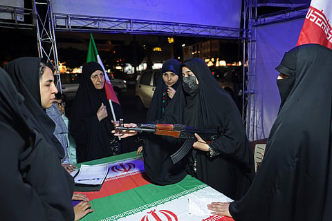 An Iranian military personnel educates women about how to use a gun at a booth in Hafte Tir Square, in Tehran on May 17, 2026.