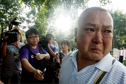Liao Dan (right) beside a group of reporters.