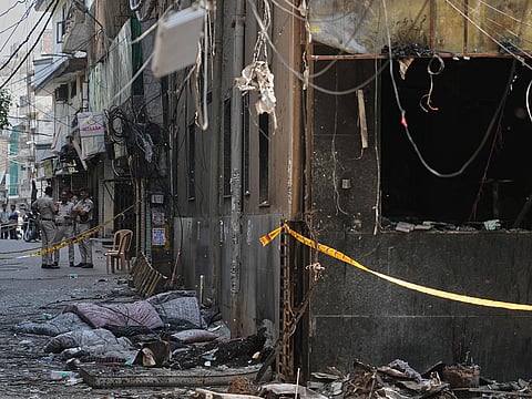 Policemen stand guard near a restaurant and hotel building that caught fire in New Delhi, India