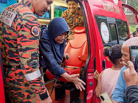 Rescuers assisting Jaslinda Saludin (2nd L) after she was found in a forested area in central Malaysia's Perak state.