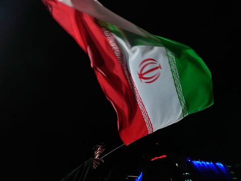 A pro-government Iranian demonstrator waves her country's flag in a gathering in Tehran, Iran.