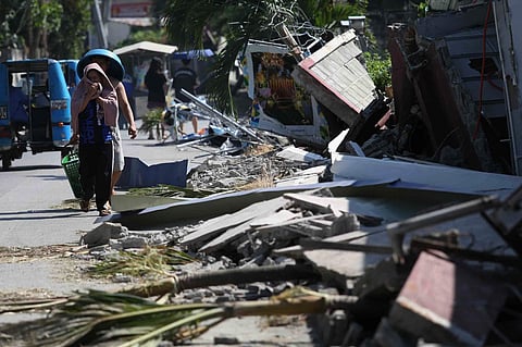 Residents walk past debris from a damaged building in General Santos, southern Philippines, Thursday, June 11, 2026, following Monday's powerful earthquake.