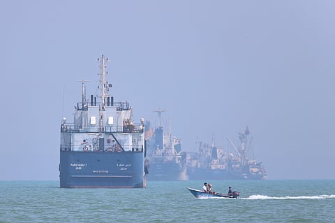 A small motorboat passes anchored vessels in the Strait of Hormuz off Bandar Abbas, Iran, Thursday, June 11, 2026.
