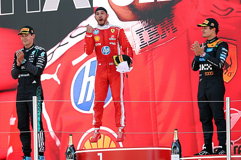 Winner Ferrari's British driver Lewis Hamilton (C), second placed Mercedes' British driver George Russell (L) and third placed McLaren's British driver Lando Norris celebrate in the podium after the Catalonia Formula One Grand Prix at the Circuit de Catalunya in Montmelo, on the outskirts of Barcelona, on June 14, 2026.