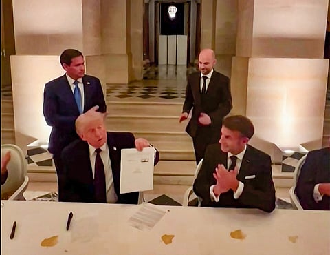 This videograb from footage made available on June 18, 2026, from the X account of French President Emmanuel Macron shows US President Donald Trump (C) and France's President Emmanuel Macron (L) during the signing of a deal with Iran to end the Middle East war, inside Chateau de Versailles, in Versailles southwest of Paris on June 17, 2026.