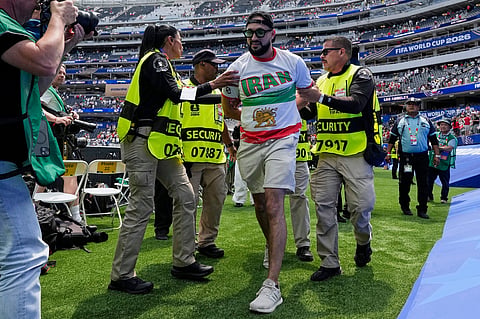An Iranian fan is removed from the pitch by security at the end of the World Cup Group G soccer match between Belgium and Iran in Inglewood, Calif., near Los Angeles, Sunday, June 21, 2026. (AP Photo/Gregory Bull)
