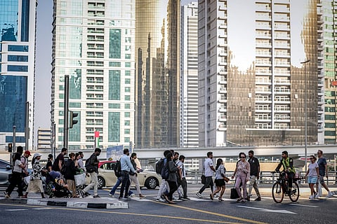 People cross a street while returning home from work, in Dubai on June 23, 2026.