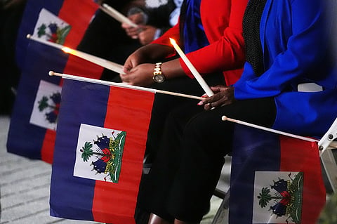 FILE - People hold Haitian flags and candles during a vigil at the Little Haiti Cultural Complex after a federal judge blocked the Trump administration from ending temporary immigration status, or TPS, for Haitians, Feb. 3, 2026, in North Miami. (AP Photo/Lynne Sladky, File)