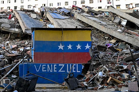 A Venezuelan flag is seen painted on a damaged wall amid the rubble of a collapsed building following earthquakes in Caraballeda, La Guaira state, Venezuela, on June 26, 2026.