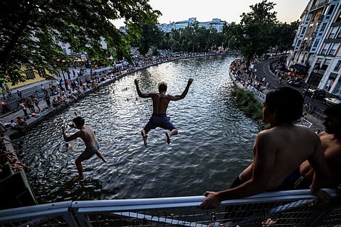 Youths jump from a bridge into the Canal Saint-Martin as France experiences a heatwave, in Paris on June 25, 2026.