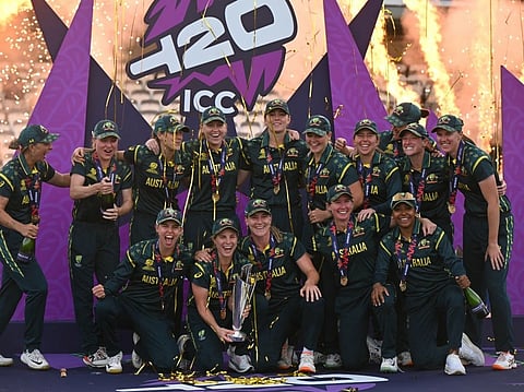 Australia's captain Sophie Molineux holds the trophy as Australia celebrate on the podium after the ICC Women's T20 cricket world cup 2026 final between Australia and England, at Lord's