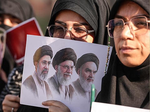 Mourners hold a placard depicting (from right) the late founder of the Islamic Republic, Ayatollah Ruhollah Khomeini, slain supreme leader Ayatollah Ali Khamenei, and current supreme leader Mojtaba Khamenei during a funeral procession for Ayatollah Ali Khamenei in Najaf on July 8, 2026.